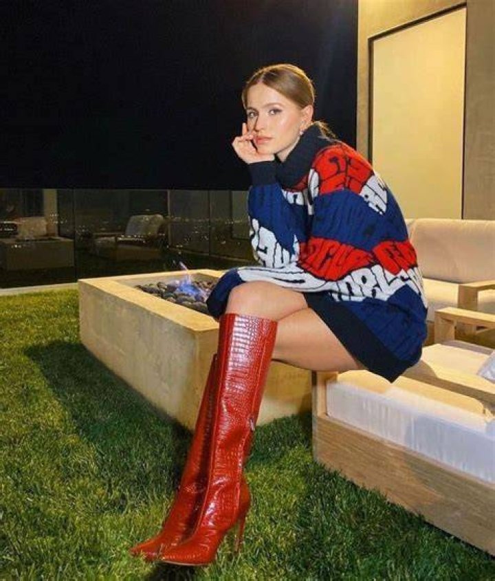 a woman wearing red knee high boots and a dress with flowers on it